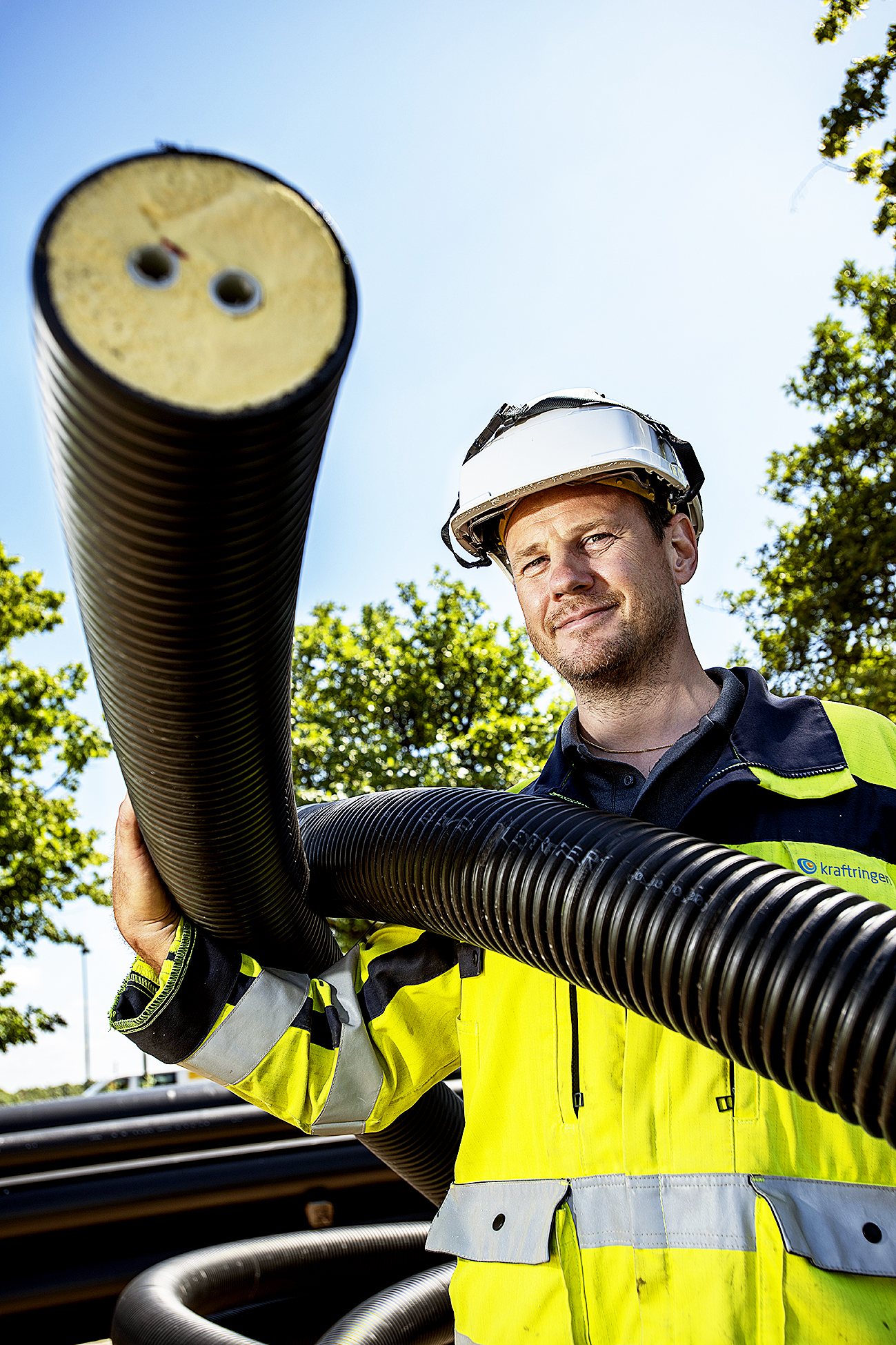 Anders Jirdén visar upp ett plaströr. I mitten syns de två mediarören för fram och returledning, med diffussionspärr mot syre och vatten. Skummet i isoleringen är nyutvecklat och har bättre isoleringsförmåga.